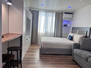 A modern bedroom with a bed, a desk, and a sofa.