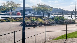 A waterfront promenade with a modern building, a red spherical sculpture, and a marina in the background. - 9 Person Holiday Home in Mandal (Lindesnes)