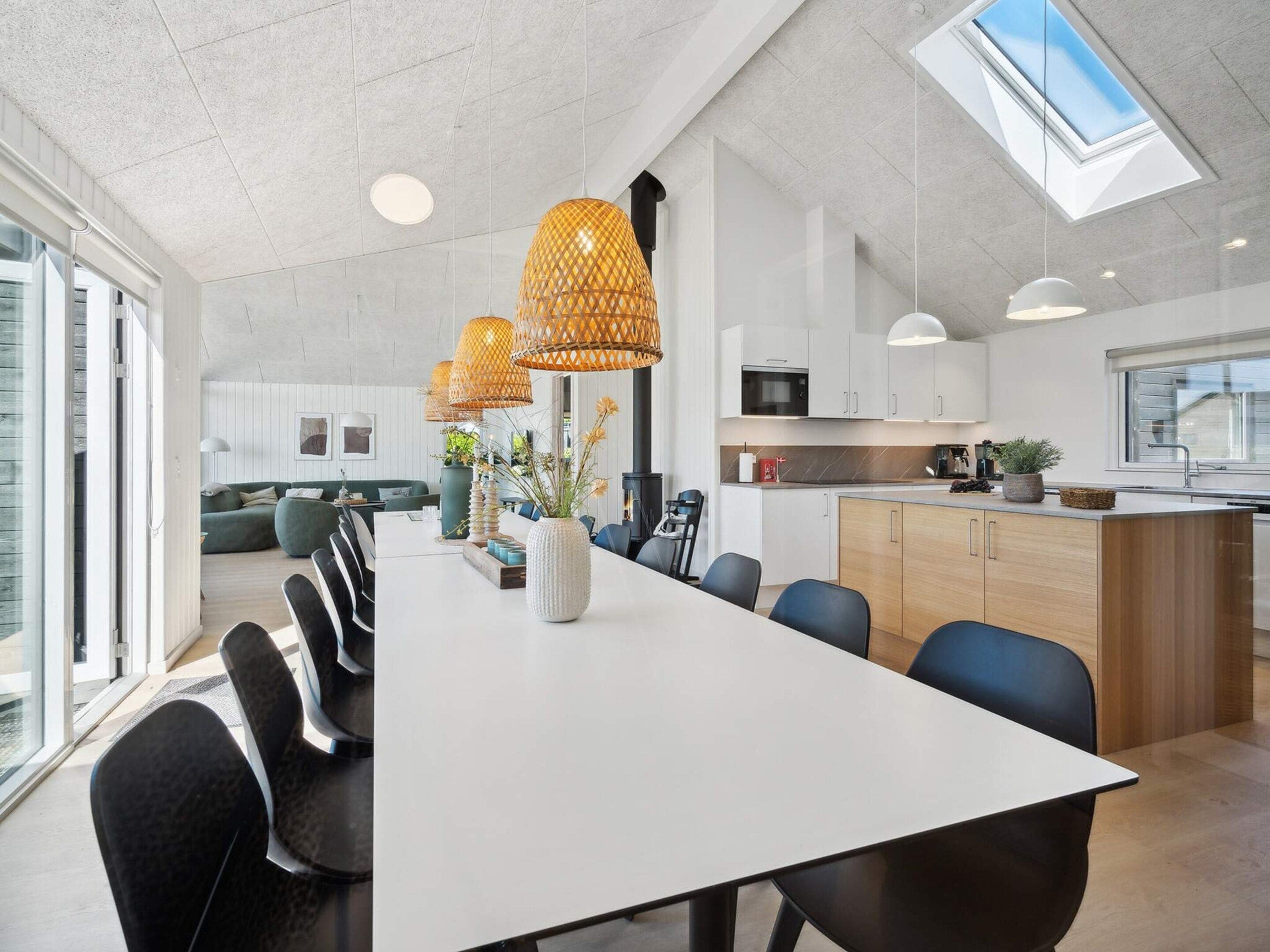 A modern kitchen with white cabinets, a central island, and a skylight.