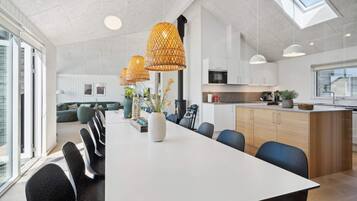 A modern kitchen with white cabinets, a central island, and a skylight.