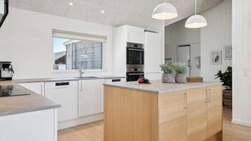 A modern kitchen with a central island, built-in appliances, and pendant lighting.