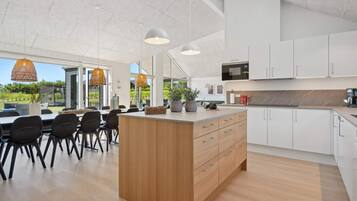 A modern kitchen with white cabinets, a wooden island, and pendant lighting.