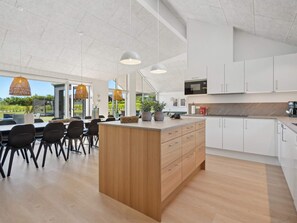Une cuisine moderne avec des armoires blanches, un îlot central en bois et des luminaires suspendus.