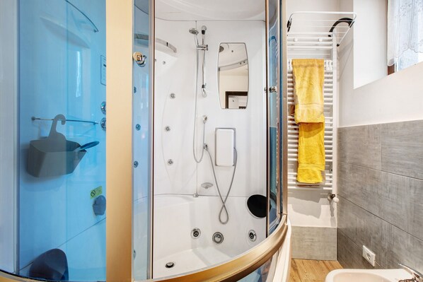 A modern bathroom with a glass-enclosed shower, a yellow towel rack, and a white sink.