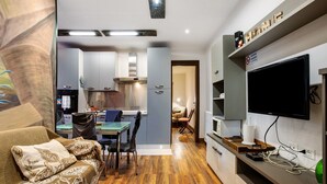 A modern kitchen with grey cabinets, a dining area with a table and chairs, and a flat-screen TV mounted on the wall. - Apartment 'Buthier' with Mountain View, Balcony and Wi-Fi (Aosta)