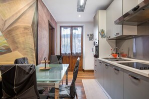 Eine moderne Küche mit einem Glastisch, Stühlen und Edelstahlgeräten.