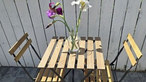 Une table en bois, un vase de fleurs et deux chaises.