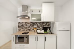 Une cuisine compacte équipée d’un four à micro-ondes, d’une cuisinière et d’un réfrigérateur Corberd.