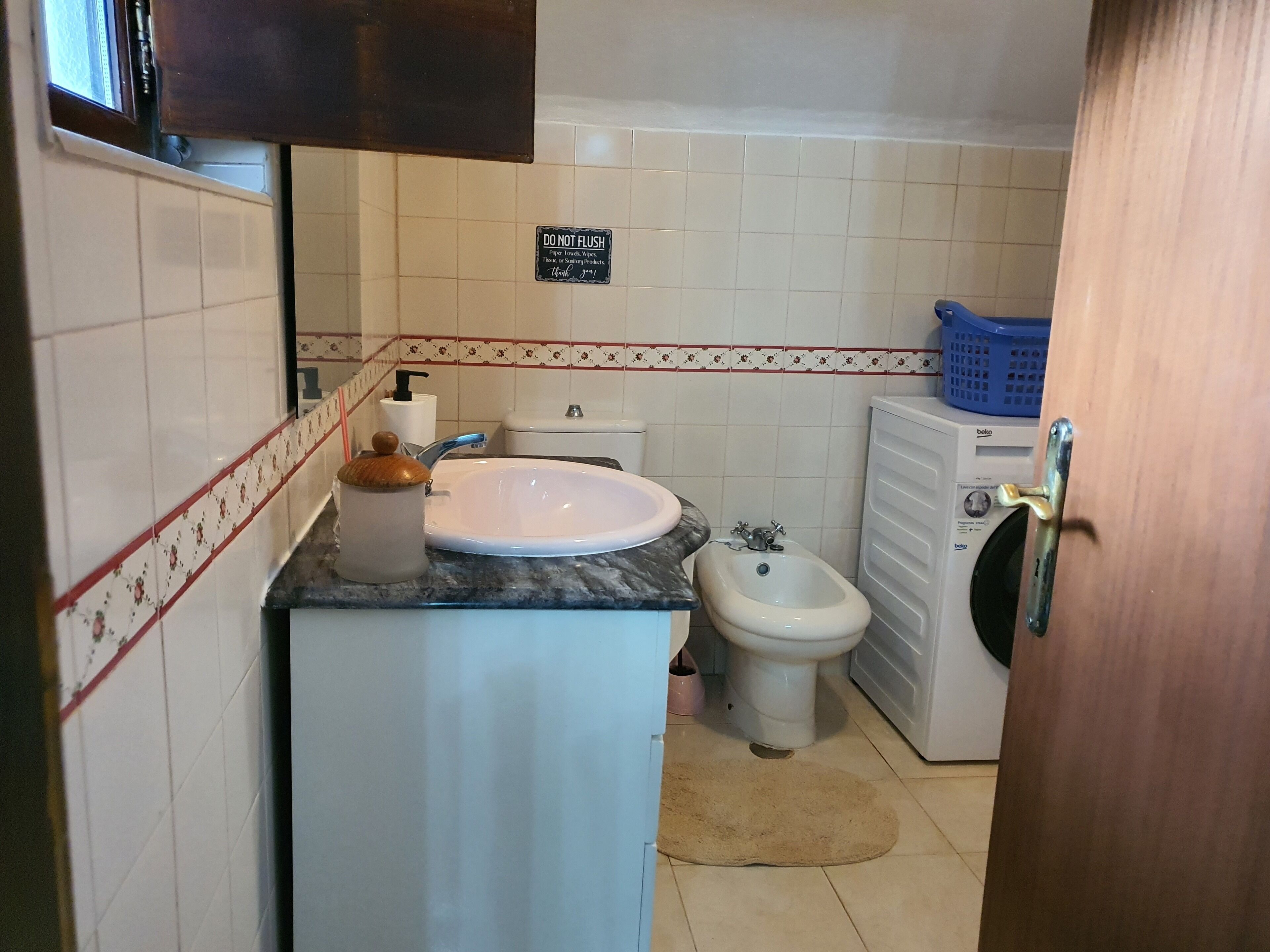 A compact bathroom with a sink, toilet, bidet, and a washing machine.