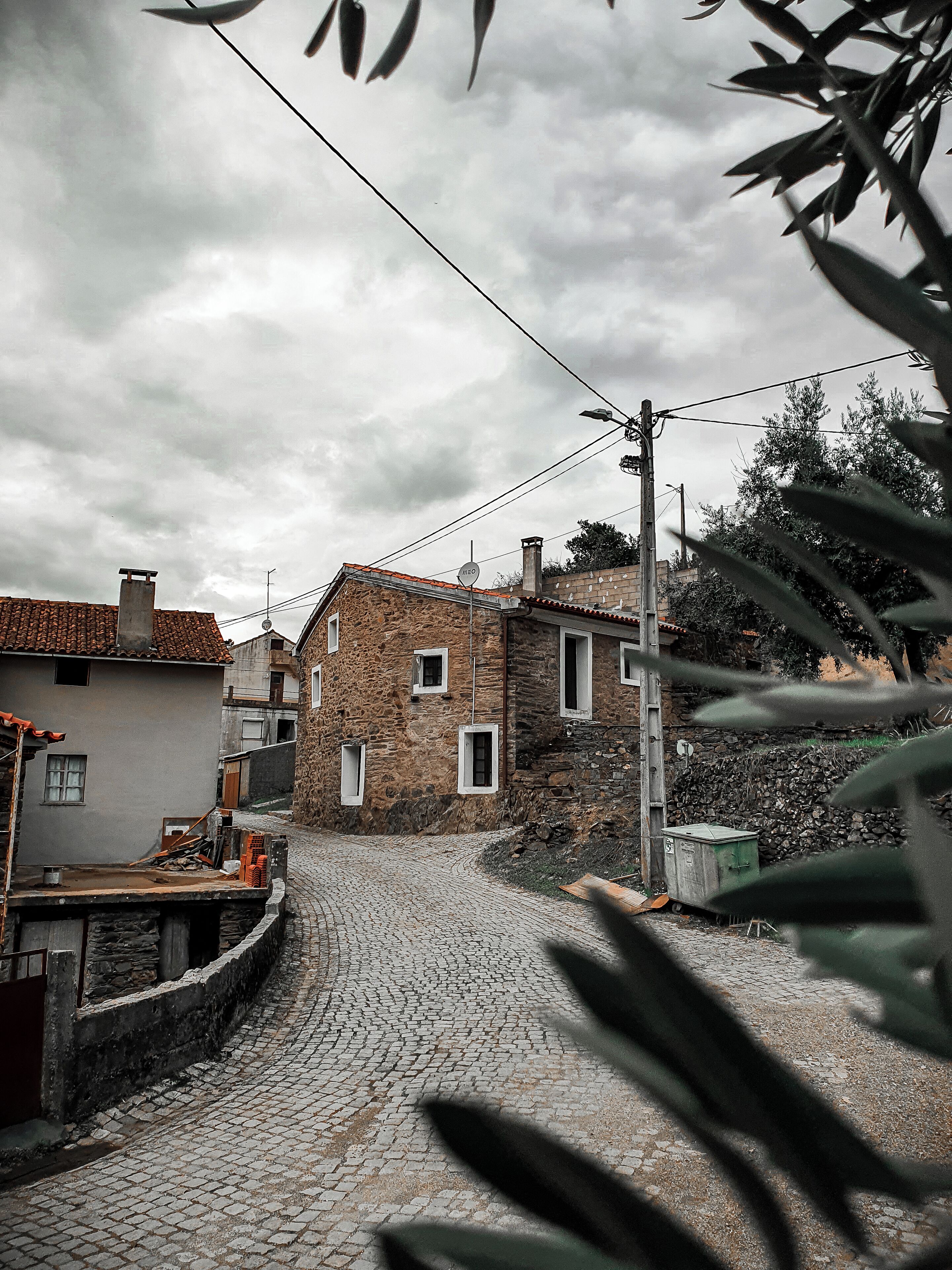 A cobblestone street in a historic town with stone buildings and a stone wall.