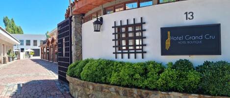 Un edificio con pared de piedra, un letrero que indica Hotel Grand Cru Boutique y un sendero pavimentado.