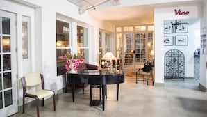 Una habitación espaciosa con un piano de cola, un sillón cómodo y una mesa de comedor con un florero.