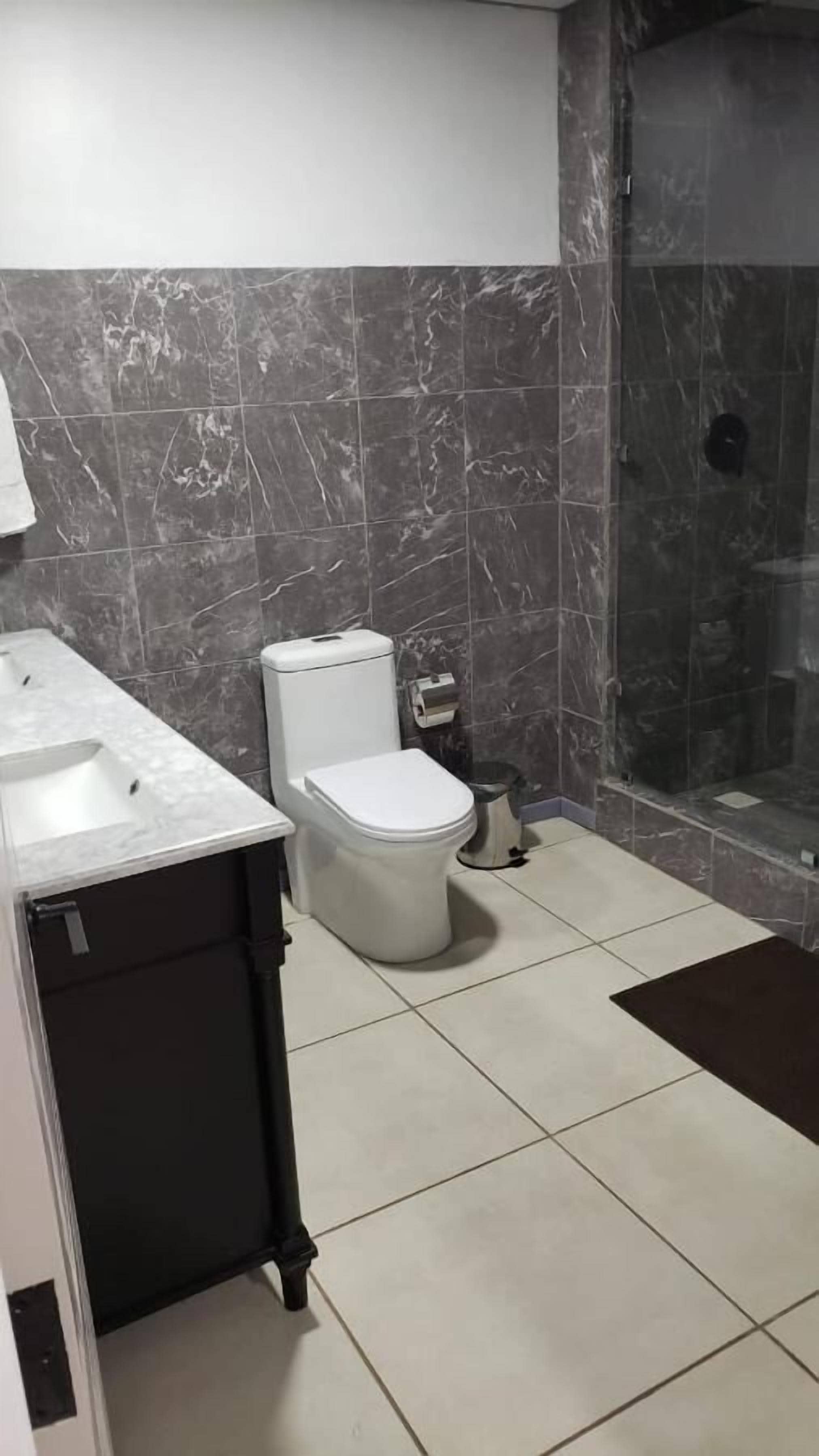 A bathroom with a toilet, sink, and shower area.