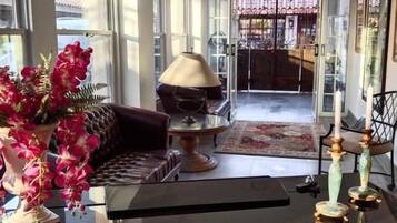 Amplia sala de estar con un gran ventanal, un sofá, una mesita de centro y un jarrón decorativo con flores.