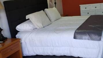 A bedroom with a bed, a nightstand, a dresser, and a painting on the wall.