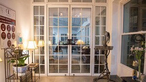 Una habitación con un gran ventanal que da a un espacio exterior, una mesita de noche con una lámpara y una planta decorativa.