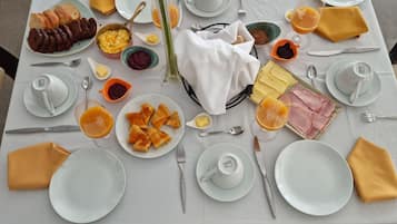 Una mesa de desayuno con platos de comida, cubiertos y un florero.