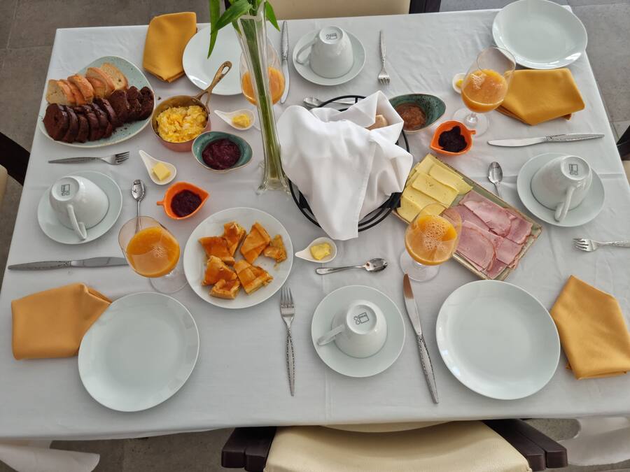 Una mesa de desayuno con platos de comida, cubiertos y un florero.