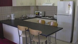 Une cuisine compacte équipée d’un réfrigérateur, d’un four à micro-ondes et d’un petit coin repas avec des chaises.