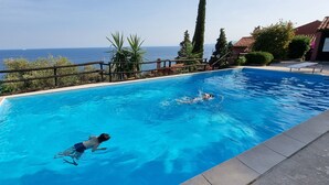 A swimming pool with clear blue water, a view of the sea, and a wooden fence. - Holiday Home 'Il Carrubo' with Sea View, Wi-Fi and Air Conditioning (Finale Ligure)