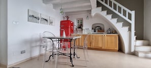 A kitchen with a red refrigerator, a dining table with clear chairs, wooden cabinets, and a staircase.