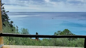 A wooden chair with a cushion on a balcony overlooking a body of water. - Holiday Home 'Il Carrubo' with Sea View, Wi-Fi and Air Conditioning (Finale Ligure)