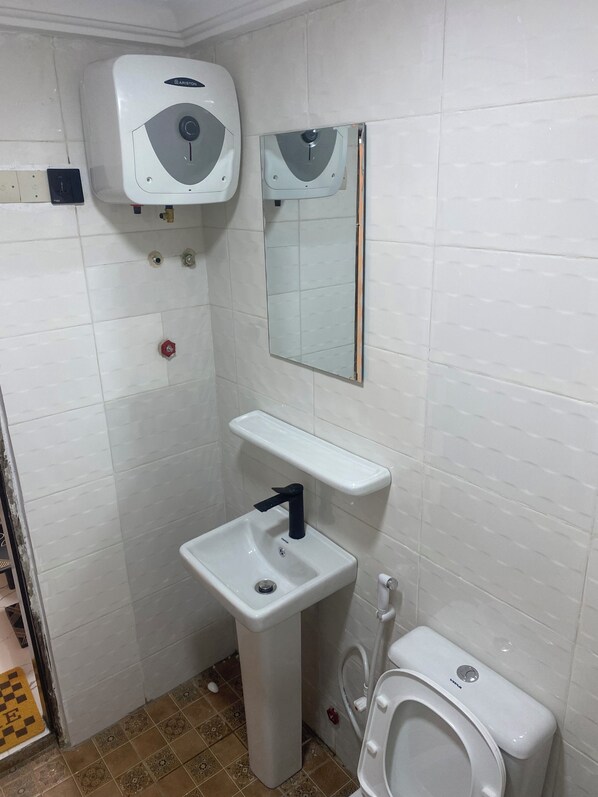 Un baño pequeño con lavamanos blanco, inodoro, espejo y dispensador de jabón.