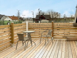 A wooden deck with two metal chairs and a small round table. - 4 Star Holiday Home in Kattarp (Kattarp)