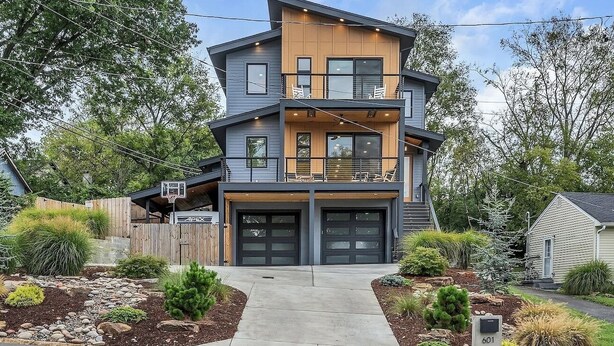 Ein modernes, zweistöckiges Haus mit Garage, Balkon und einem gepflegten Garten.