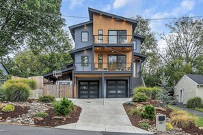Een modern herenhuis met garage, balkon en een verzorgde tuin.