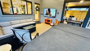 Ein modernes Wohnzimmer mit einem grauen Sofa, einem Glastisch und einem an der Wand befestigten Fernseher.