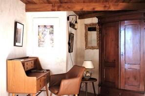 Una habitación con un escritorio de madera, un sillón de cuero, una lámpara y un mueble grande de madera.