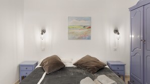 Ein Schlafzimmer mit einem Bett, zwei Nachttischen, einem Kleiderschrank und einem Bild an der Wand.