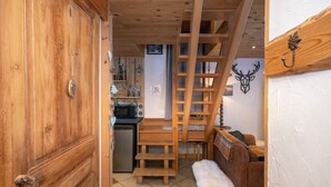Un interior de madera con una escalera, una zona de cocina y una decoración de cabeza de venado montada en la pared.