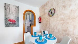 A dining area with a white table, blue placemats, and white chairs.