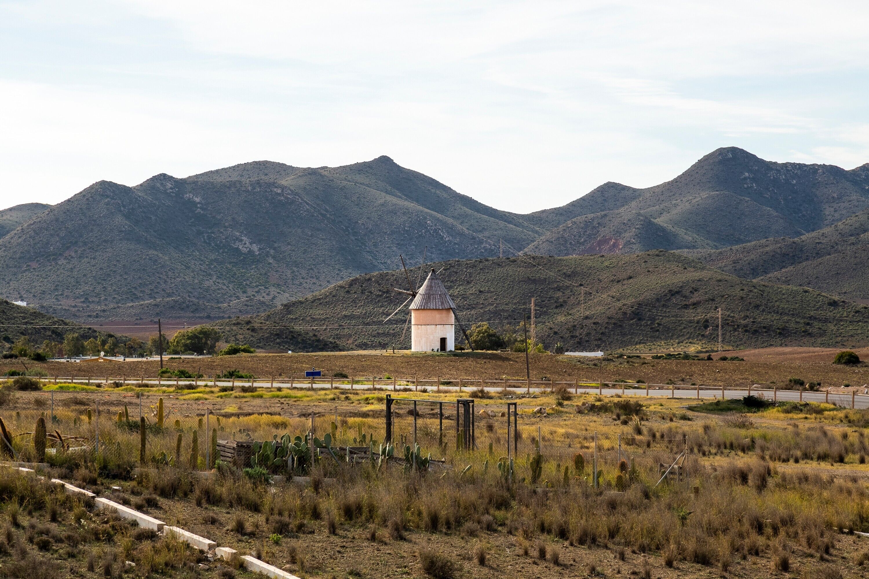 Un moulin à vent dans un paysage rural, avec des montagnes en arrière-plan.