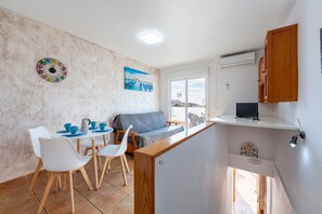 Un espacio habitable compacto con kitchenette, comedor y sofá.