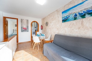 A living room with a gray sofa, a dining table with chairs, a painting of Venice, and a mirror. - Apartment 'Maracas 2' with Mountain View, Private Terrace and Air Conditioning (El Pozo de los Frailes)
