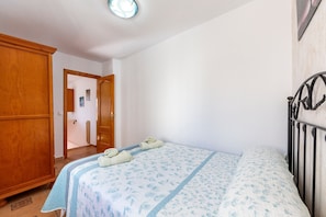 A bedroom with a bed, a wooden wardrobe, and a door leading to another room. - Apartment 'Maracas 2' with Mountain View, Private Terrace and Air Conditioning (El Pozo de los Frailes)