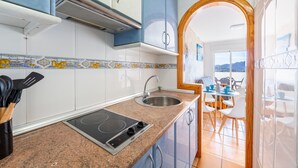 A kitchen with a built-in stove, sink, and blue cabinets.