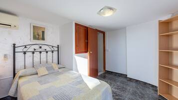 Un dormitorio con cama, armario, estantería e iluminación en el techo.
