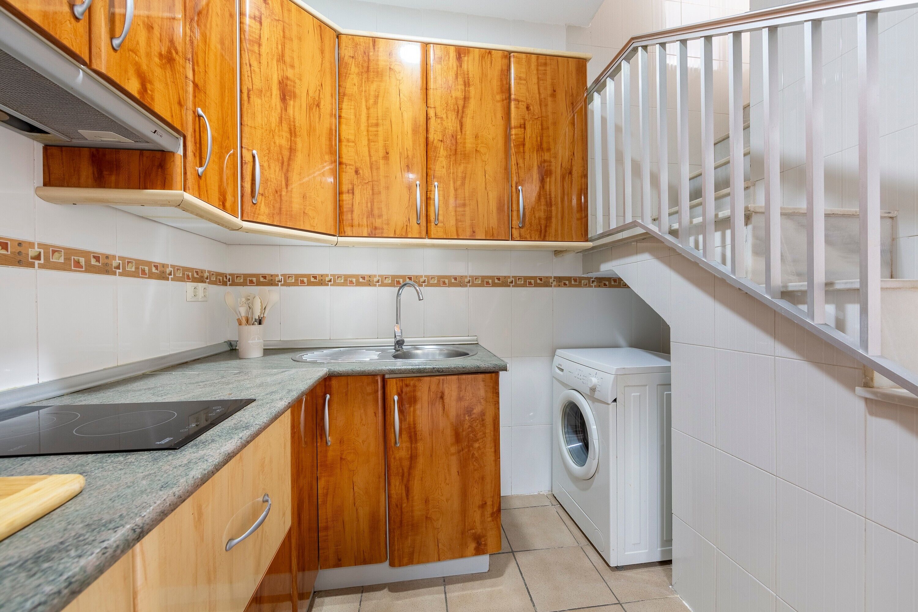 A kitchen with wooden cabinets, a built-in stove, a sink, and a washing machine.