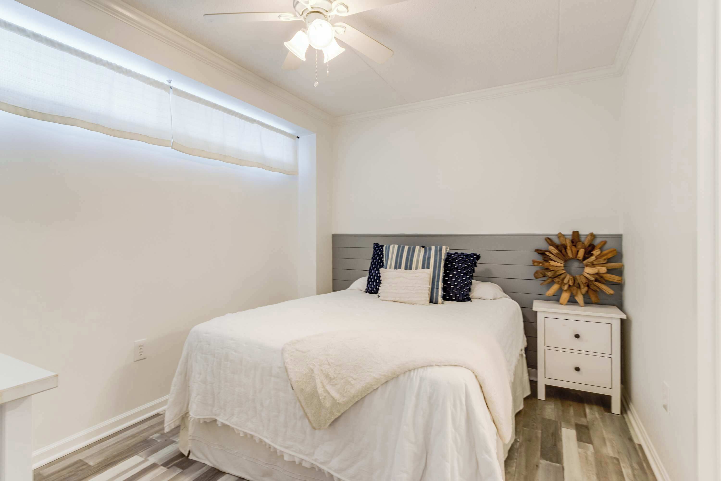A bedroom with a bed, nightstand, and a decorative wall piece.