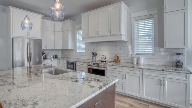 A modern kitchen with white cabinetry, a granite countertop, a stainless steel refrigerator, a double oven, and a built-in dishwasher. - Private Pool Rehoboth Beach House Seven Bedrooms! (Dewey Beach)