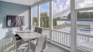 A covered patio with a table and chairs, large windows, and a view of a backyard with a pool. - Private Pool Rehoboth Beach House Seven Bedrooms! (Dewey Beach)