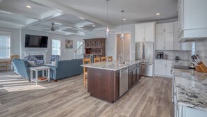 A spacious living area with a large island, a kitchen with white cabinets, and a dining area with a blue sofa. - Private Pool Rehoboth Beach House Seven Bedrooms! (Dewey Beach)
