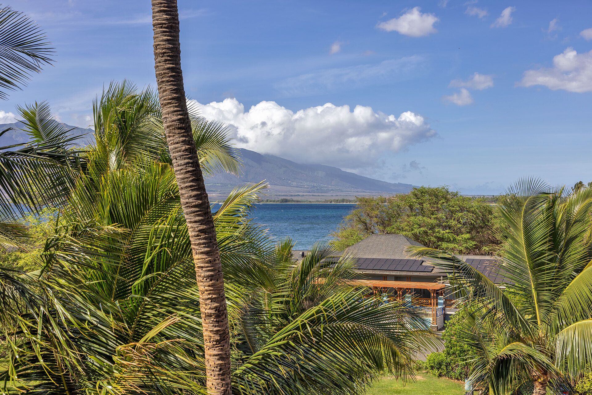 Paisagem tropical com vista para uma montanha, um corpo d'água e um gazebo.