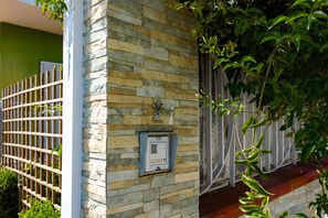 A stone wall with a security intercom and a metal gate.