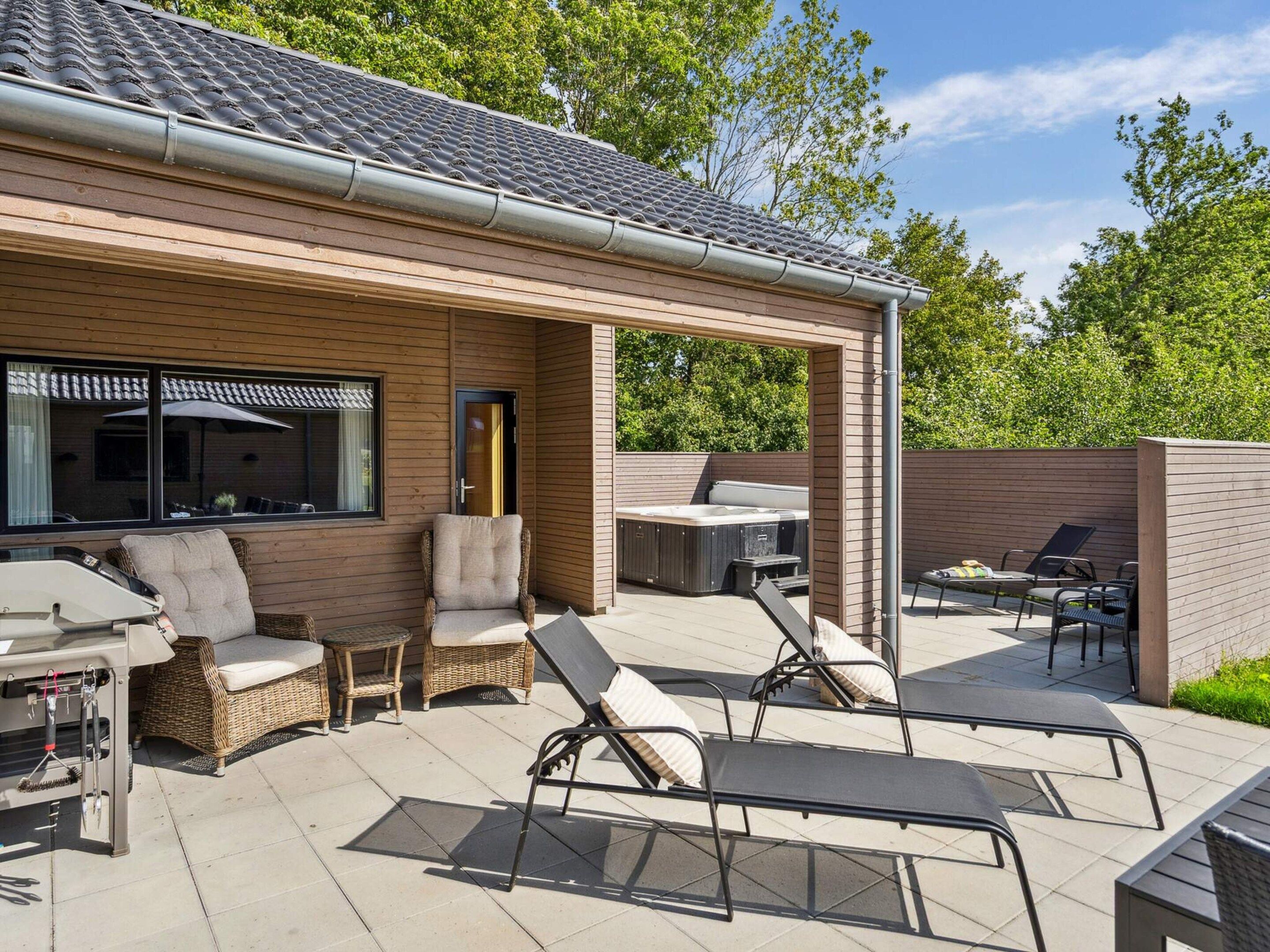 A covered outdoor patio with seating, a hot tub, and a barbecue area.