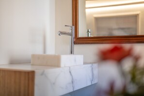 Une salle de bain avec un lavabo en marbre, un meuble-lavabo en bois et un miroir.